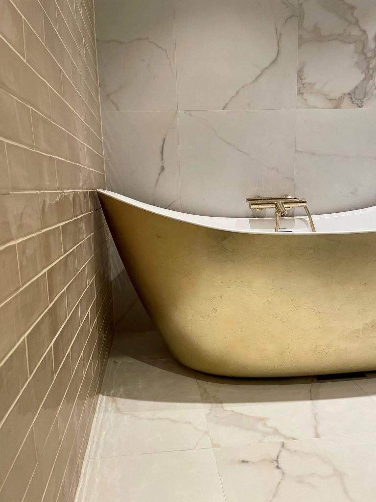 Et badekar i gull skaper en elegant og inspirerende stemning på badet.